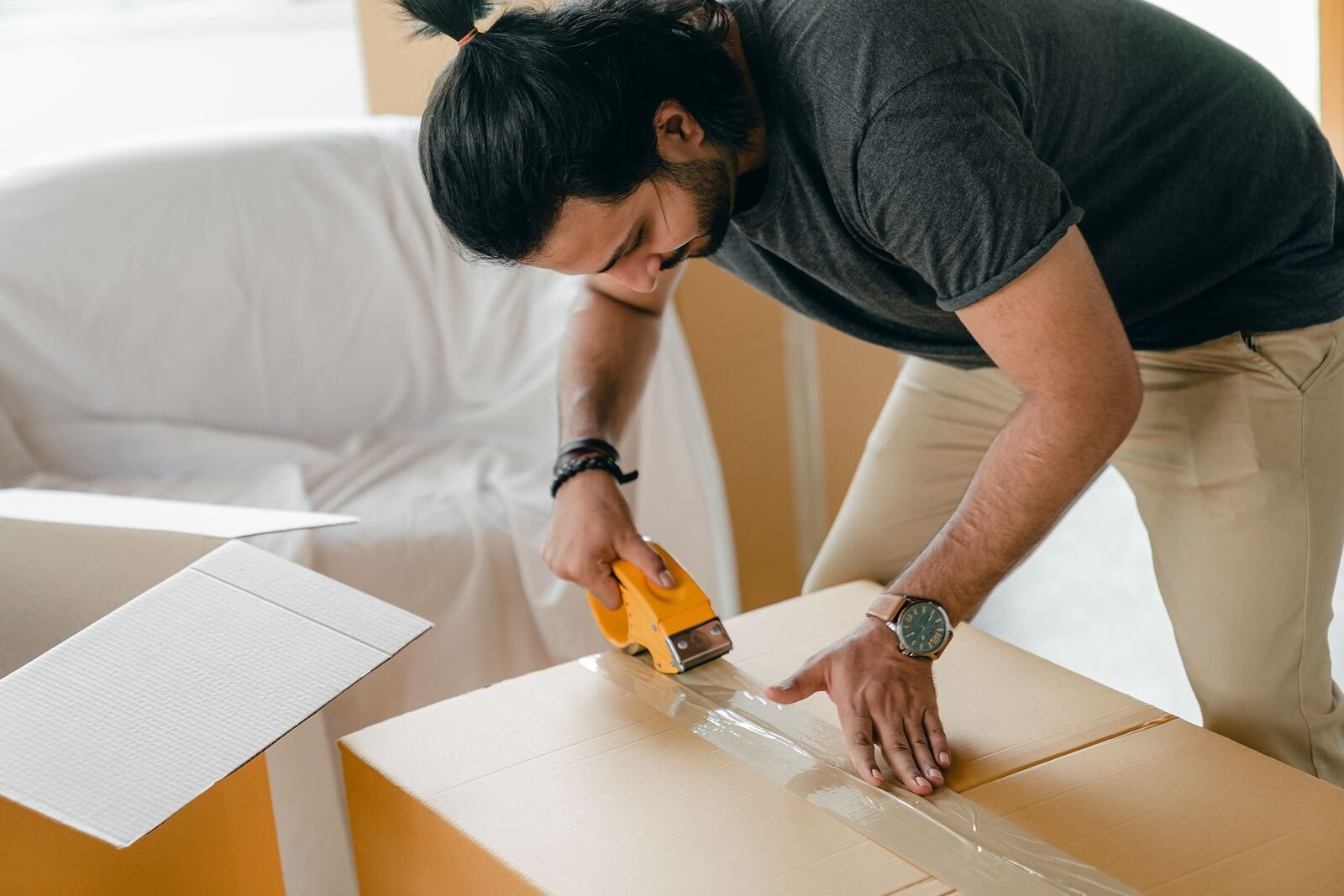Person packing and taping a cardboard moving box for storage